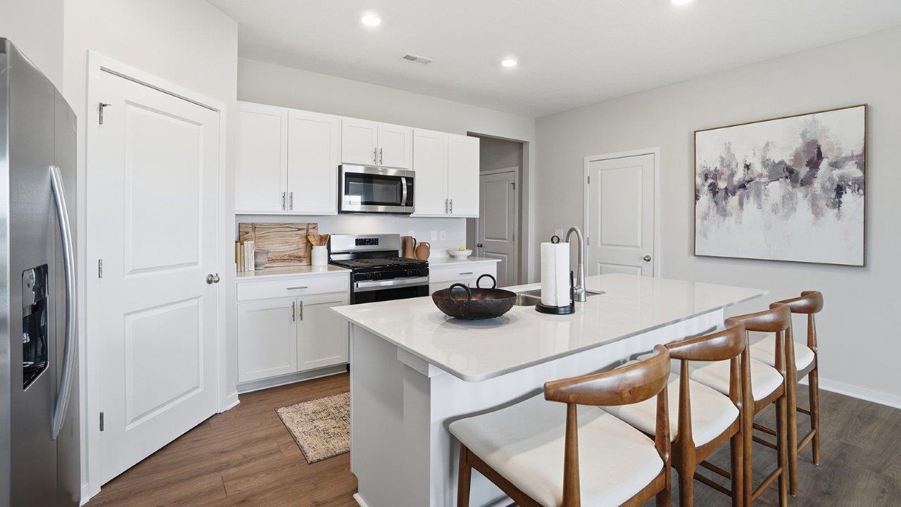 kitchen with white cabinets, built in island, corner pantry and stainless steel appliances