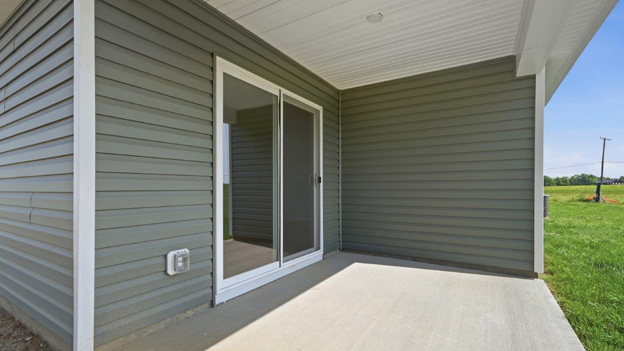 single story home with green siding and covered patio rear exterior