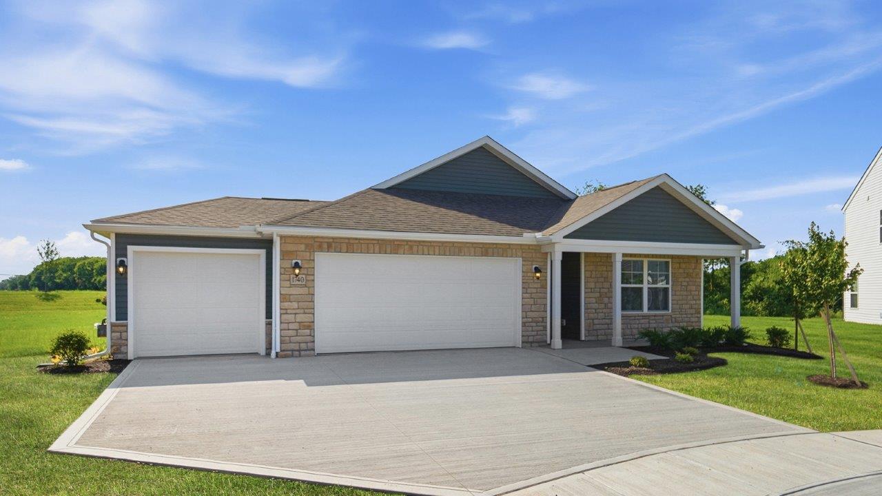 single story home with green siding, partial stone front, covered front porch and three car garage