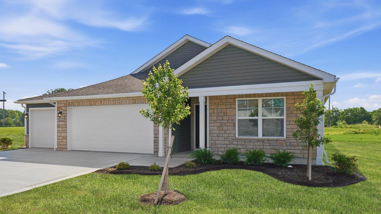 single story home with green siding, partial stone front, covered front porch and three car garage
