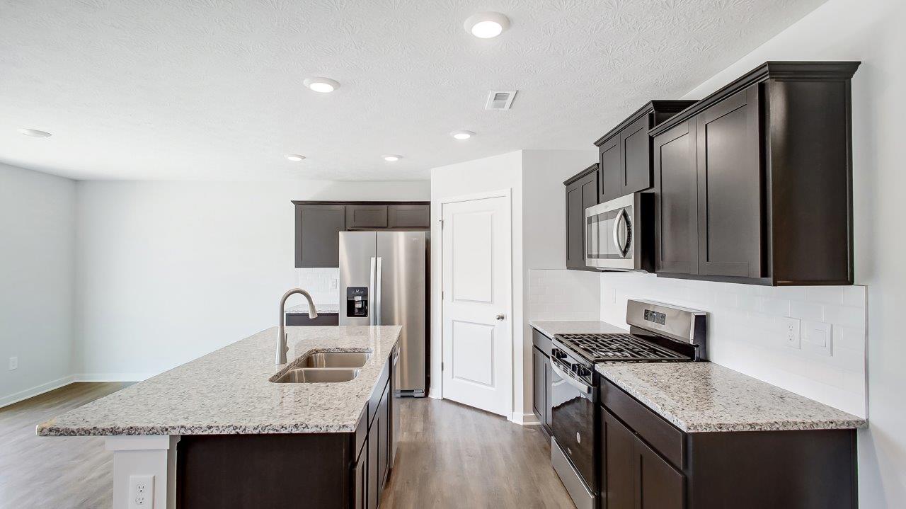 kitchen with brown cabinets, built in island, stainlesd steel appliances and corner walk in pantry