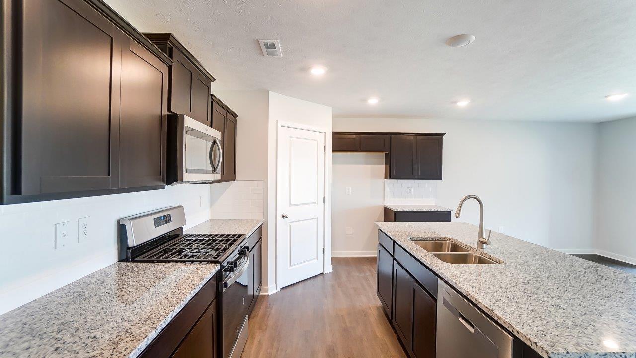 kitchen with brown cabinets, hard surface counters, corner walk in pantry