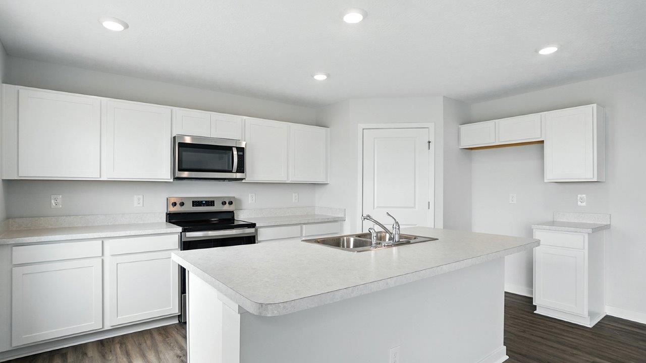 kitchen with white cabinets, built in island, stainless steel appliances and corner walk in pantry