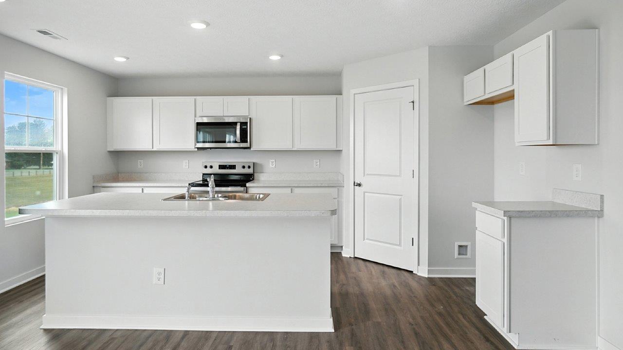 kitchen with white cabinets, built in island, stainless steel appliances and corner walk in pantry