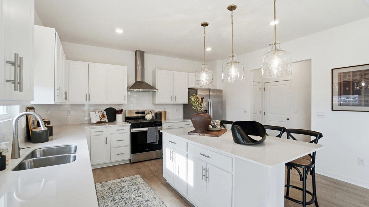 kitchen with white cabinets, built in island with bar seating, stainless steel appliances, walk in pantry and pendant lighting