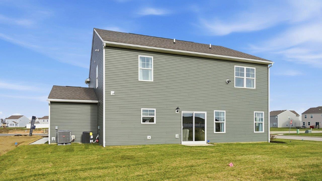two story home with green siding and three car garage rear exterior