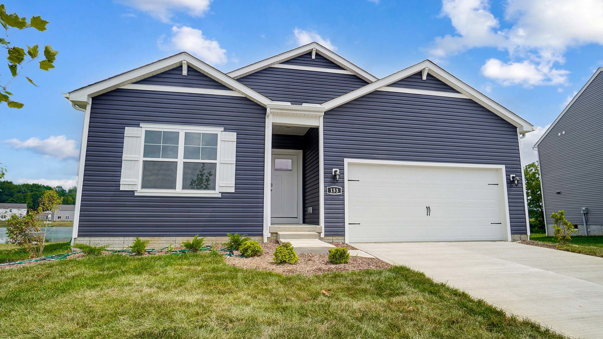 single story home with blue siding, covered entry and two car garage