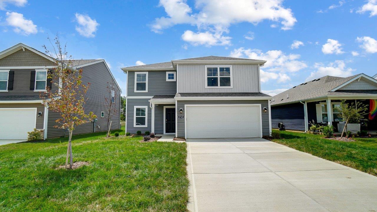 two story home with grey siding, covered entry and two car garage