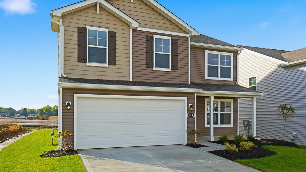 two story home with brown siding, covered front porch, two car garage