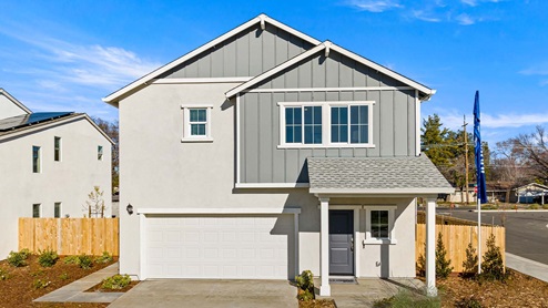 Two-story home with light gray exterior and blue siding and a covered patio and two-car garage.