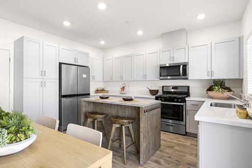 Amber Lynn Estates Plan 1547 Open concept kitchen with island, soft gray cabinets, white countertops and stainless-steel appliances.