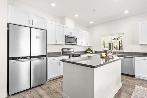 Amber Lynn Estates Plan 1811 Kitchen island with gray countertops, white cabinets and stainless-steel appliances.