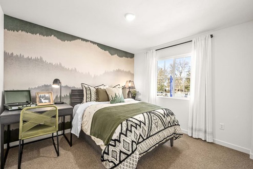 Amber Lynn Estates Plan 1811 Bedroom with paned window with full length curtains and tree-line wallpaper.