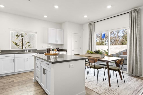 Amber Lynn Estates Plan 1811 Kitchen island with gray countertops, white cabinets, dining area and sliding glass door.