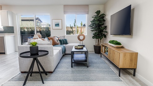 Spacious living area with window view of backyard and sliding glass door to patio
