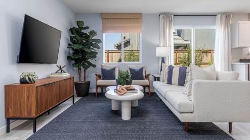 Spacious living area with window view of backyard and sliding glass door to patio