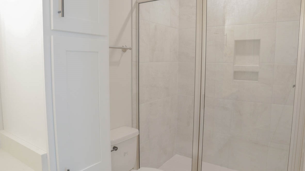 En suite bathroom with white cabinets, quartz countertops, and a shower and tub combination with gray marbled tile.