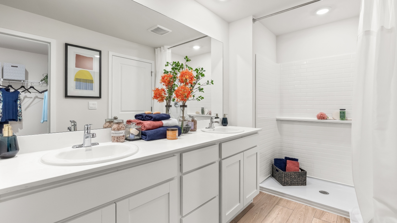 Inside of the Jemison model bathroom. White cabinet bathroom vanity with dual sinks. Plank tile floors with a white shower.