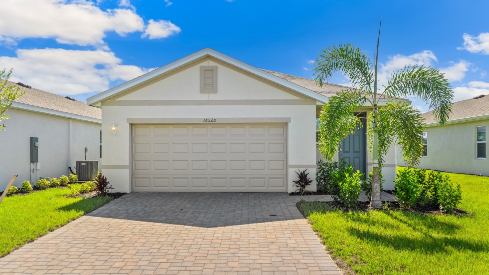 Outside of the Harper model G. Cream colored home with two car garage, window, and front door. Mixed paver driveway.