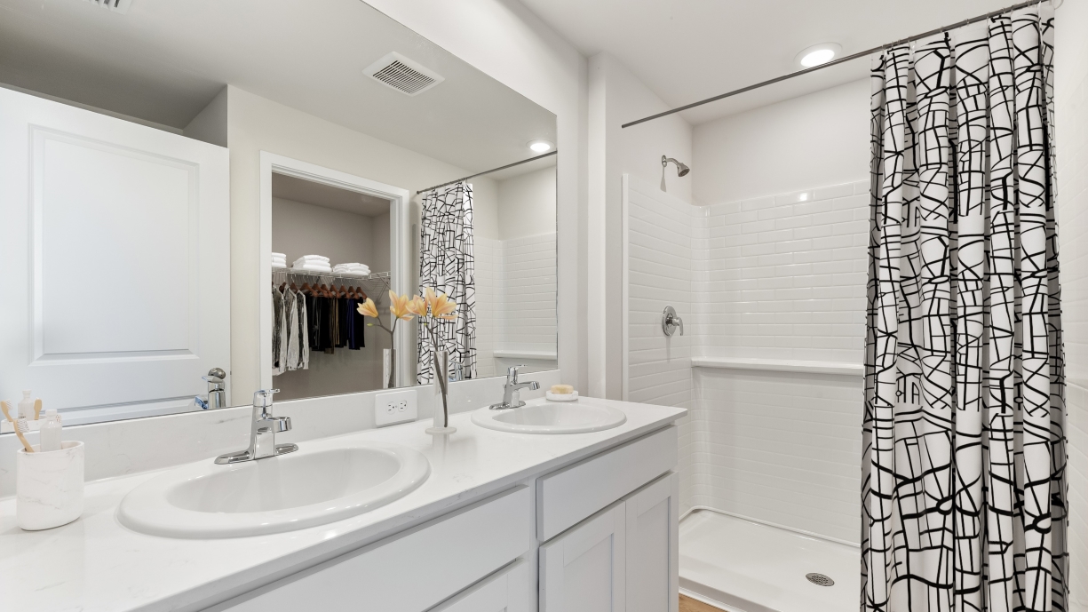 Inside of the primary bathroom. Dual vanity sinks, walk in shower, and quartz countertops