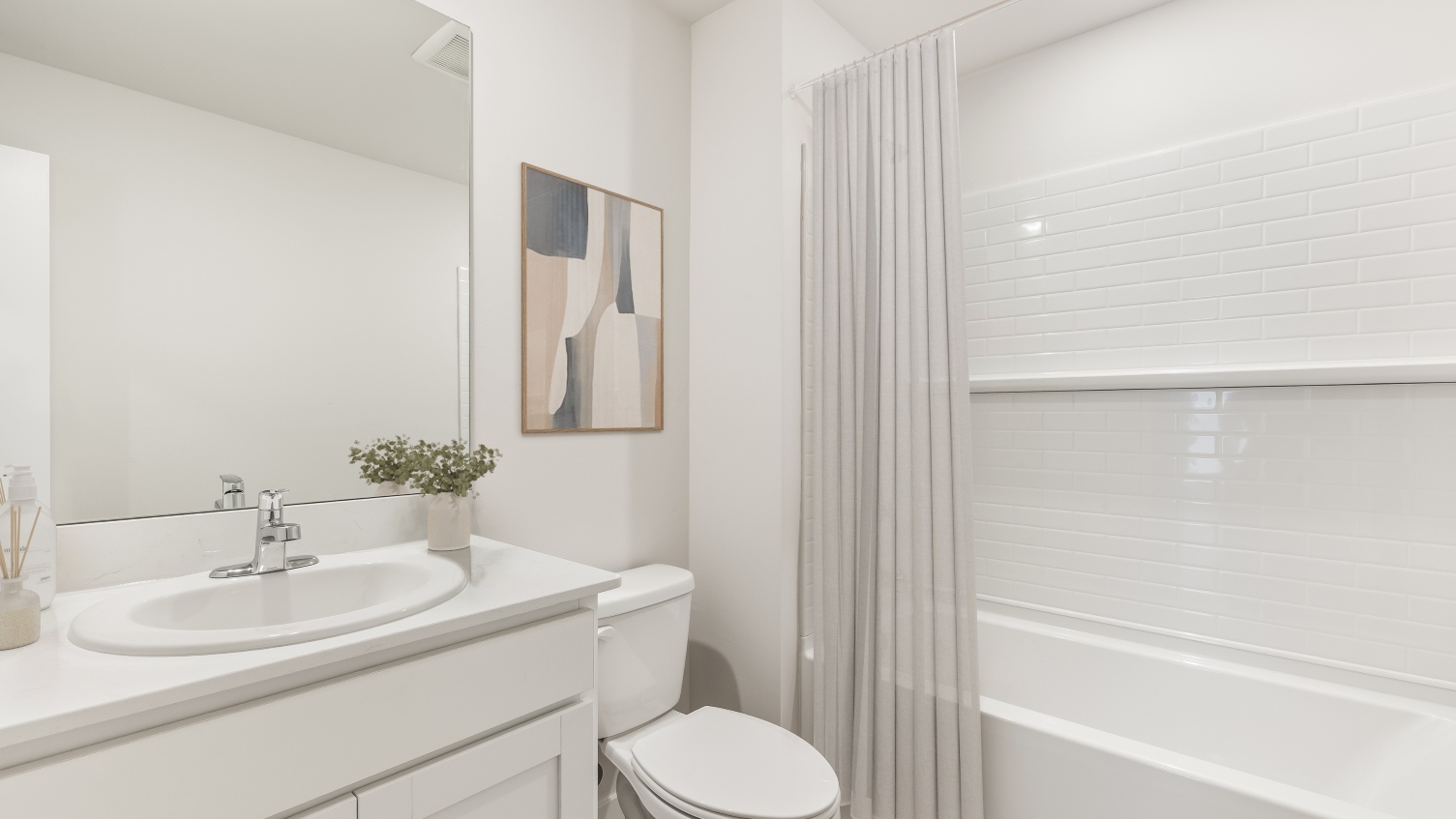 Inside the Downing model bathroom 2. white cabinet and countertops with a dual sink vanity. White shower. Closet across from vanity.