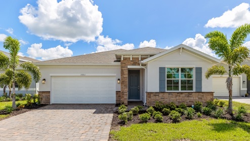 Outside of the Clifton model B. Brown home with two car garage, one window with shutters, and front door. Mixed paver driveway.
