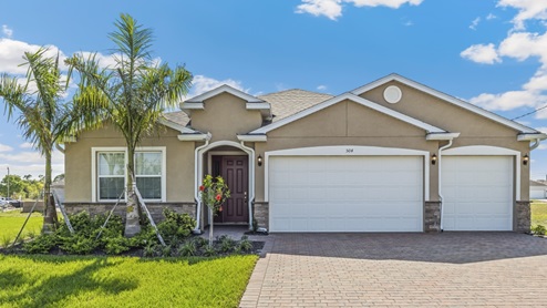 Outside of the Destin model. Brown home with two car garage, front door, and window in the front. Mixed paver driveway.