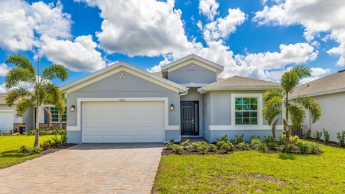 Outside of the Shelby B model. Blue home with two car garage, window, and front door. Mixed paver driveway.
