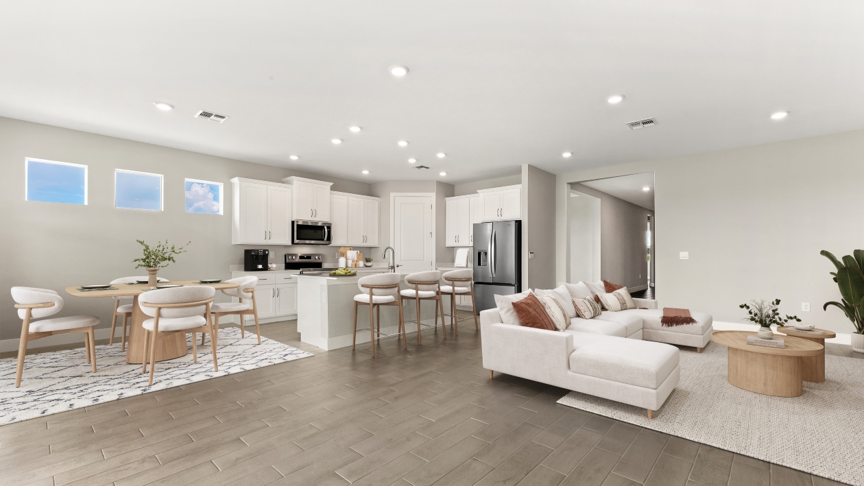 Inside of the Shelby model home Living room, Kitchen and Dining room  with three little windows above the dining area. There is bar seating in the Kitchen.