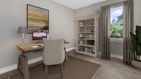 Inside of the Delray B model den. Wood tile floors with off-white walls. Room contains desk with laptop, chair, and shelf with nick-nacks on it. Room has a window.