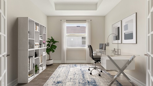 Inside of the Shelby model den. Wood tile flooring with off-white walls. Room contains storage shelf, table with laptop, and chair. Room also has window.