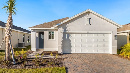Outside of the Allex model C. Beige home with two car garage, window, and front door. Mixed paver driveway.