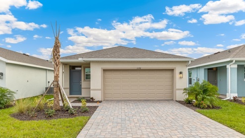 Outside of the Harper model G. Blue colored home with two car garage, window, and front door. Mixed paver driveway.