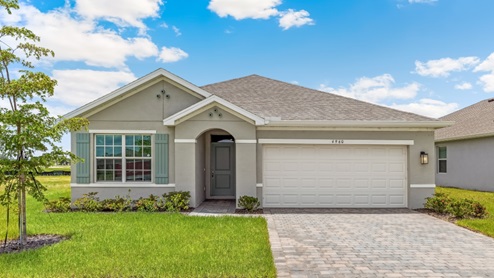 Outside of the Aria C model. Green home with one car garage, one window, and front door. Mixed paver driveway.