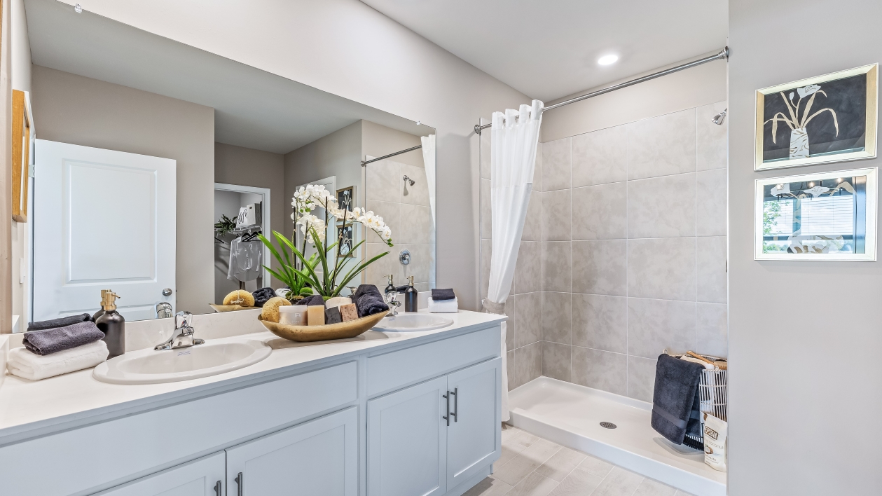 The Master Bathroom has a tiled shower with white cabinetry and silver fixtures. There is plenty of space for two people with the dual sink counter.