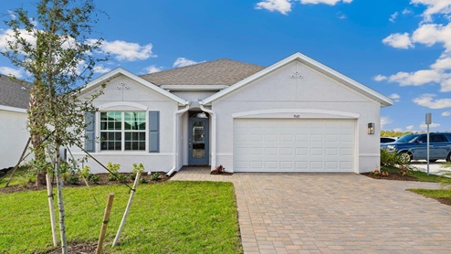 Outside of the Cali model home. Gray home, two car garage, window with shutters, and front door. Mixed paver driveway.