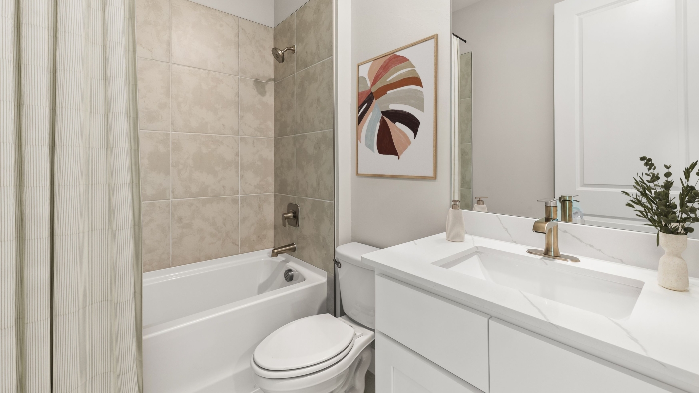 Inside of the Shelby secondary bathroom. A tub shower and Vanity sinks