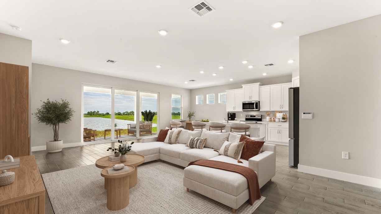 Inside of the Shelby model home Kitchen with stainless steel appliances. Living room couch from this angle and patio sliding doors to outside dining area.
