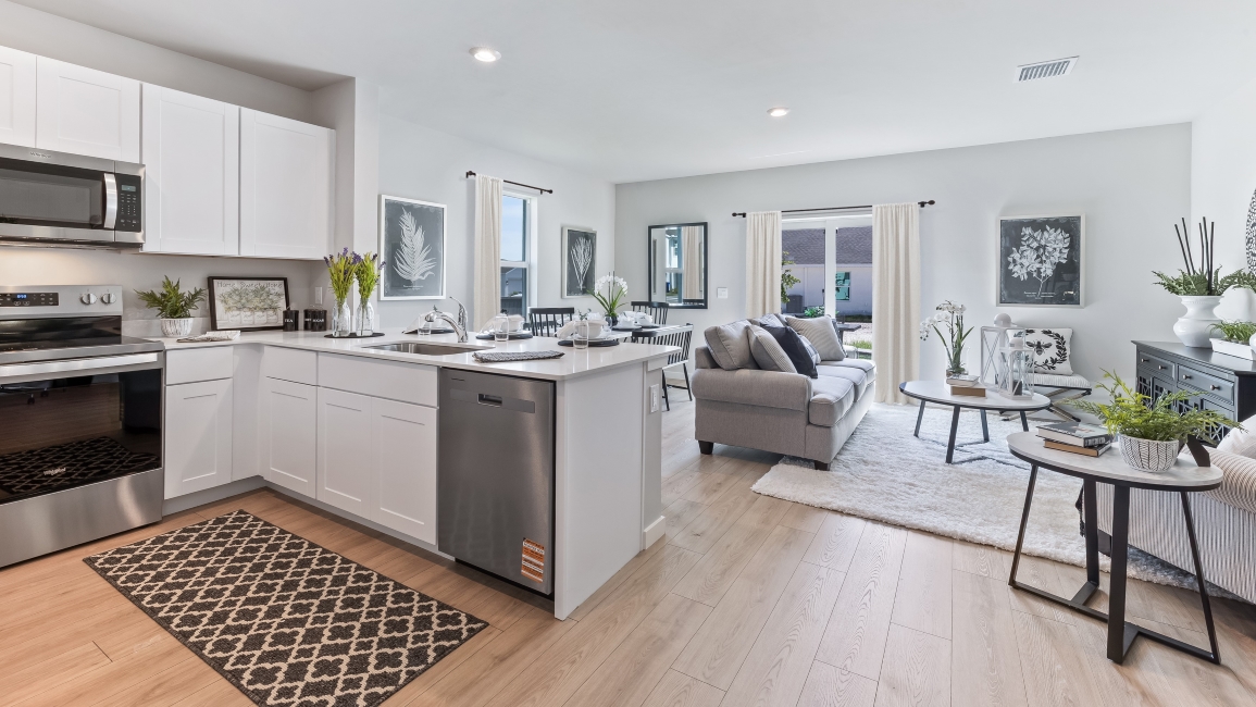 Inside the Pearson model kitchen. White cabinets with stainless steel appliances and bar seating.
