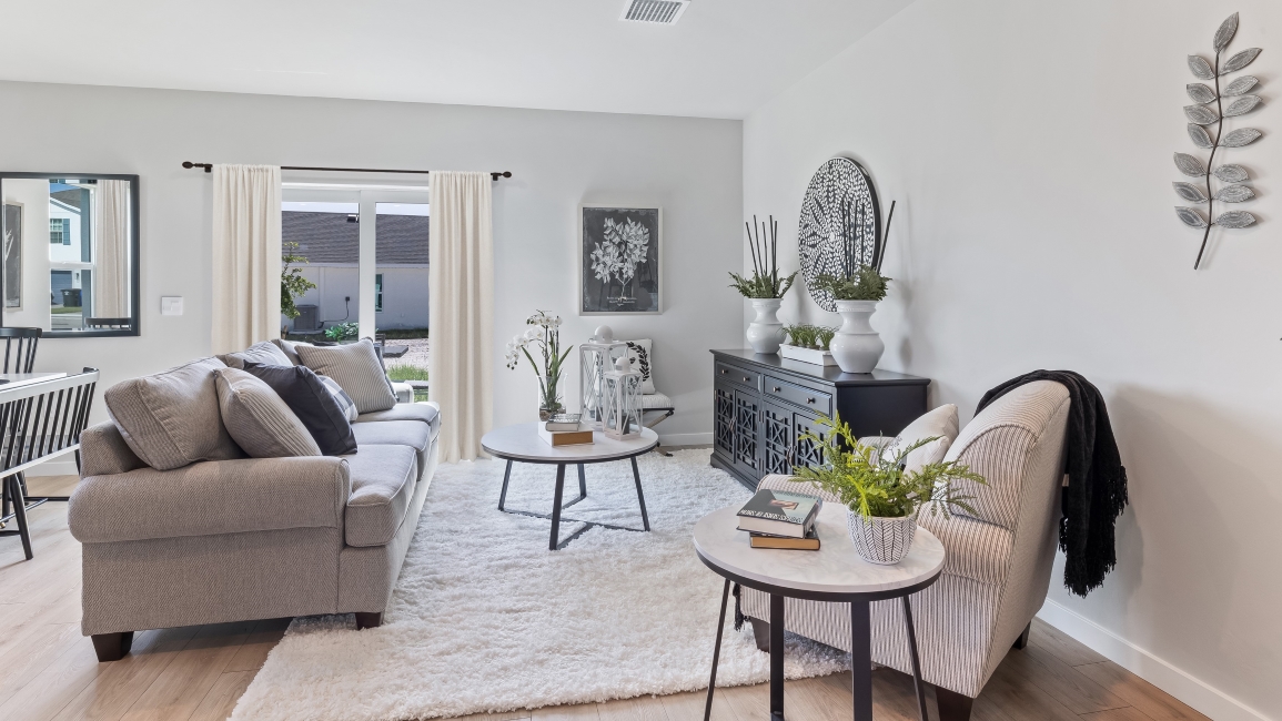 Inside the living room of the Pearson model. White walls with revwood floors. One couch and chair with storage chest.