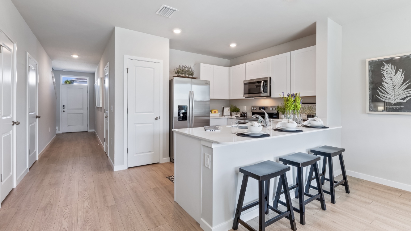 Inside the Pearson model kitchen. White cabinets with stainless steel appliances and bar seating.