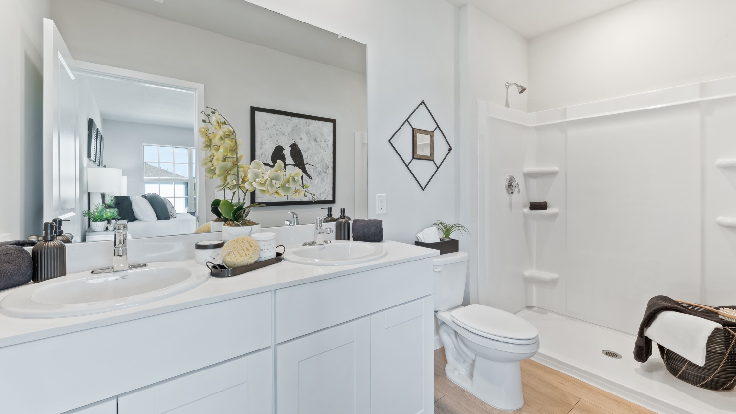 Inside bathroom 2 of the Pearson. Has dual vanity sinks, white cabinets, and a white shower.