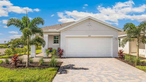Exterior elevation of light gray home with white trim and tan paver driveway.