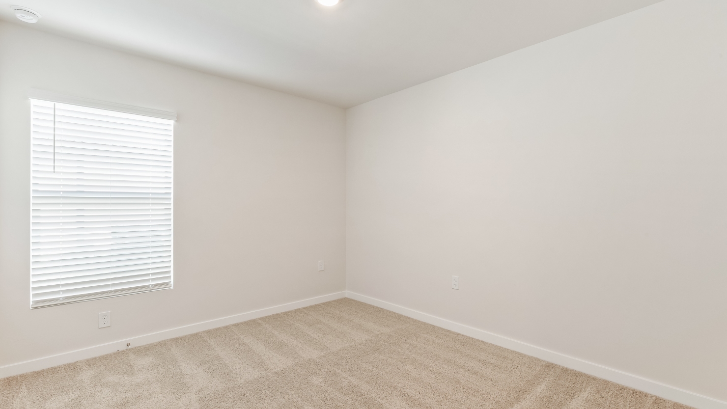 Inside of the Cameron B mocel bedroom. Off-white carpet with white walls.
