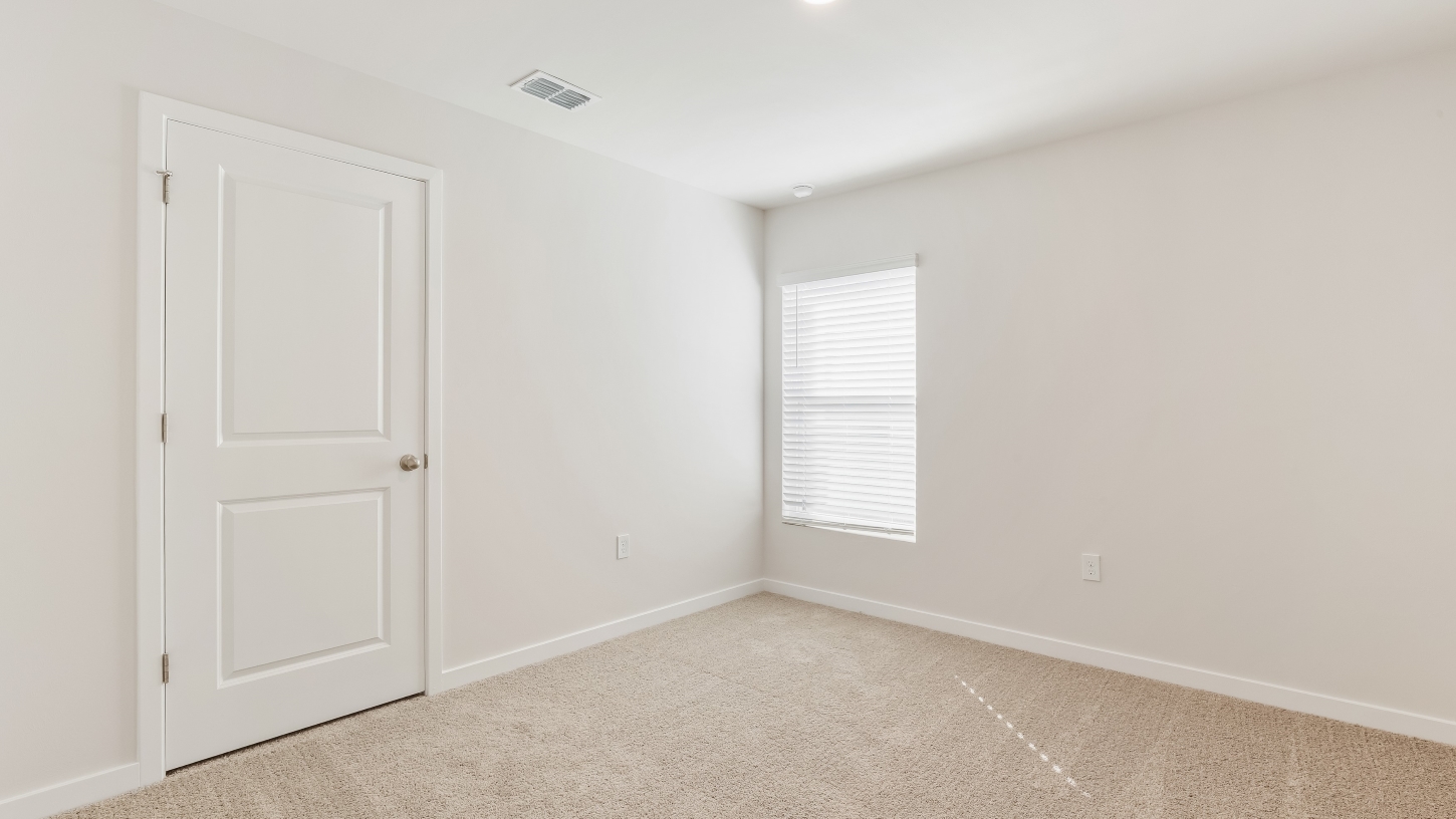 Inside of the Cameron B mocel bedroom. Off-white carpet with white walls.