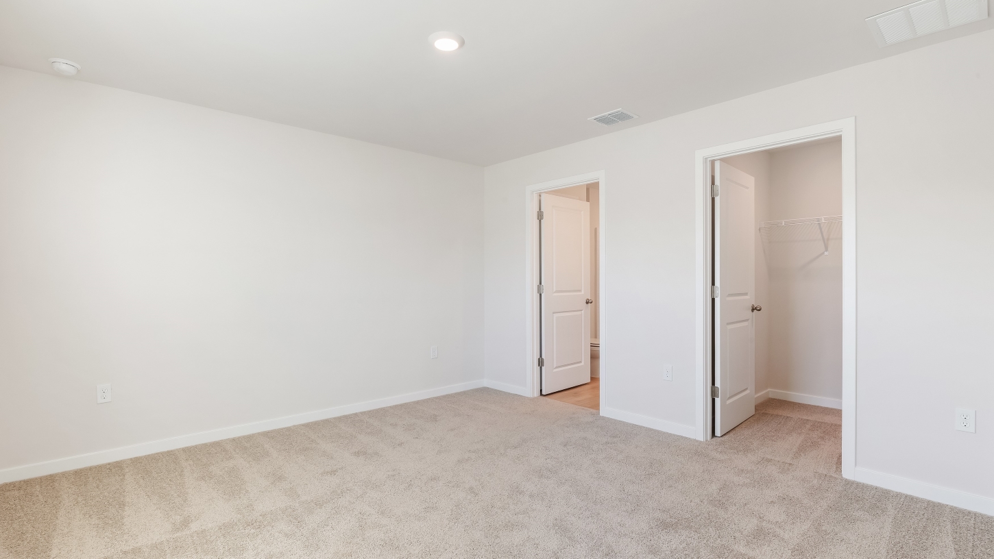 Inside of the Cameron B mocel bedroom. Off-white carpet with white walls.