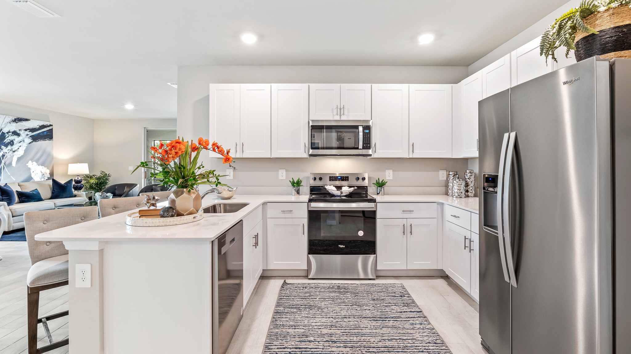 Inside the Carrington model kitchen. Stainless steel appliances and white cabintery with quartz countertops.