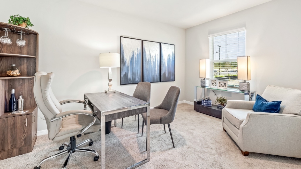 Inside the Carrington Model study/den fits a desk, chairs, bookshelf and seating arrangment across the desk and chairs