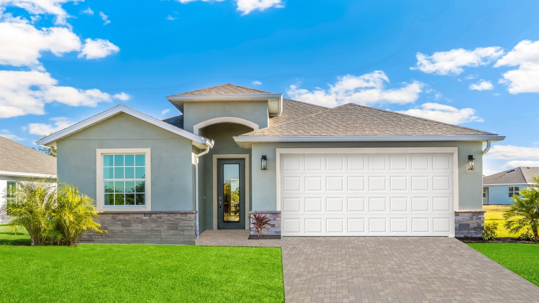 Outside of the Lantana model. Green home with a 2 car garage, front door, window, and a mixed pavers driveway.