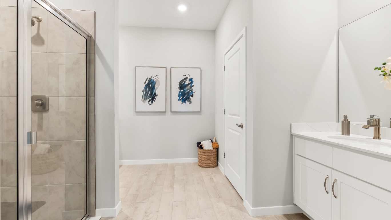 Inside the Lantana model bathroom. White cabinets and counter top sink vanity. Tile shower.